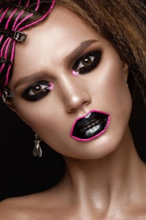 A beautiful girl with a black creative make-up and a pink thread on her lips. Beauty face. Photos shot in studio