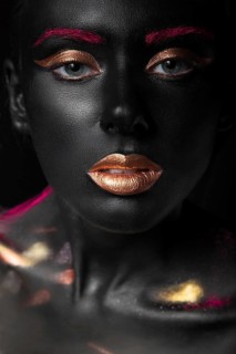 Fashion portrait of a dark-skinned girl with color make-up.Beauty face. Picture taken in the studio on a black background