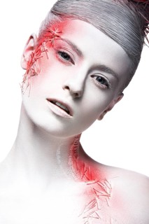 Art fashion girl with white skin and red paint on the face. Creative art beauty. Picture taken in the studio on a black background