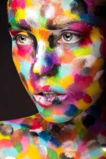 Girl with colored face painted. Art beauty image. Picture taken in the studio on a black background