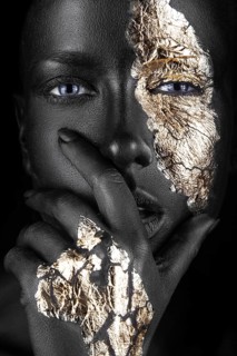 Fashion portrait of a dark-skinned girl with gold make-up.Beauty face. Picture taken in the studio on a black background