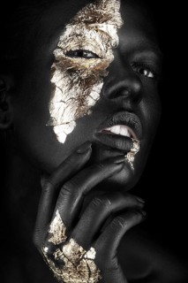Fashion portrait of a dark-skinned girl with gold make-up.Beauty face. Picture taken in the studio on a black background