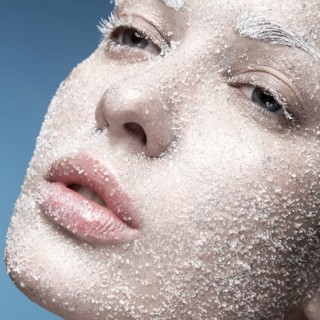 Portrait of a girl with pale skin and sugar snow on her face. Creative art beauty fashion. Picture taken in the studio on a blue background