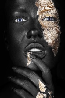 Fashion portrait of a dark-skinned girl with gold make-up.Beauty face. Picture taken in the studio on a black background