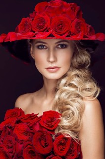 Beautiful blond girl in a dress and hat with roses