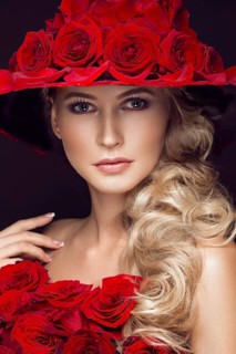 Beautiful blond girl in a dress and hat with roses