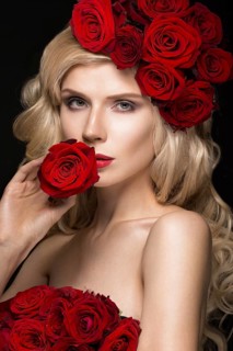 Beautiful blond girl in a dress and hat with roses