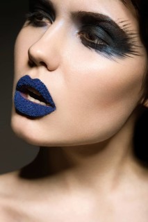 Portrait of beautiful girl with unusual blue lips and eyes closed. Picture taken in the studio on a gray background