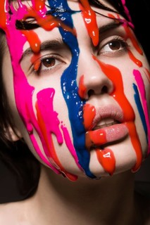 Portrait of a beautiful Girl with red paint on her face. Photo shot in the Studio on a black background