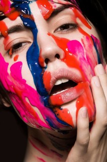 Portrait of a beautiful Girl with red paint on her face. Photo shot in the Studio on a black background