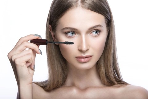 Beautiful young girl with a light natural make-up and beauty tools in hand. Picture taken in the studio on a white background