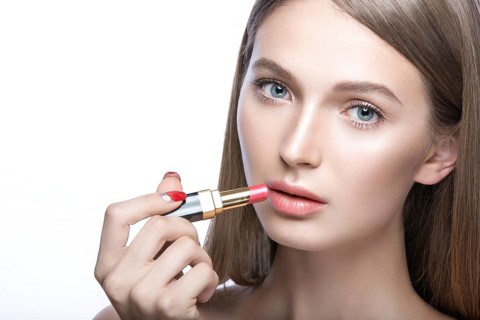 Beautiful young girl with a light natural make-up and beauty tools in hand. Picture taken in the studio on a white background