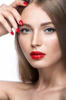 Beautiful young girl with a bright make-up and red nails. Picture taken in the studio on a white background