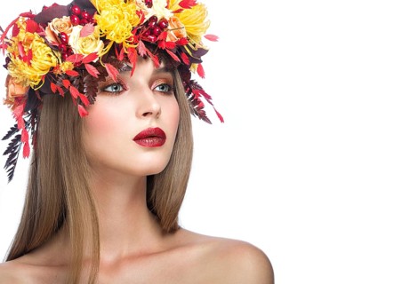 Beautiful girl with bright autumn wreath of leaves and flowers. Beauty face. Picture taken in the studio on a white background