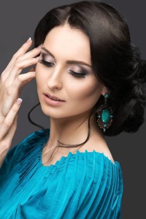 Beautiful girl in a blue dress with evening make-up and hairstyle. Beauty face. Picture taken in the studio on a black background. Hairstyle back view