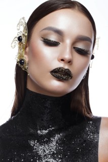 Beautiful girl with black creative art make-up and gold accessories. Beauty face. Photos shot in studio