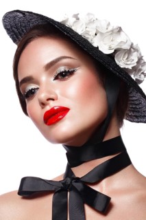 Beautiful girl in a black hat with flowers and retro makeup. Beauty face. Photo taken in the studio