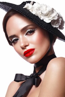 Beautiful girl in a black hat with flowers and retro makeup. Beauty face. Photo taken in the studio