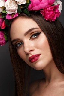 Beautiful girl with bright make up and flowers on her head. Beauty face. Photos shot in studio
