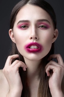Girl with pink lipstick smeared across his face. Creative makeup. Picture taken in the studio