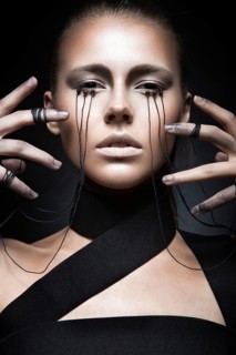 Beautiful girl with creative make-up in Gothic style and the threads of eyes. Art beauty face. Picture taken in the studio on a black background