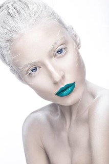 Beautiful girl in the image of albino with blue lips and white eyes. Art beauty face. Picture taken in the studio on a white background