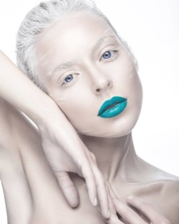 Beautiful girl in the image of albino with blue lips and white eyes. Art beauty face. Picture taken in the studio on a white background