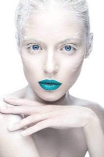 Beautiful girl in the image of albino with blue lips and white eyes. Art beauty face. Picture taken in the studio on a white background