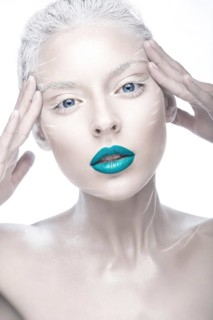 Beautiful girl in the image of albino with blue lips and white eyes. Art beauty face. Picture taken in the studio on a white background