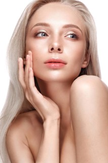 Beautiful young girl with a light natural make-up and perfect skin. Beauty face. Picture taken in the studio on a white background