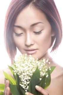 Fashion beautiful girl oriental type with delicate natural make-up and flowers. Beauty face. Picture taken in the studio on a white background