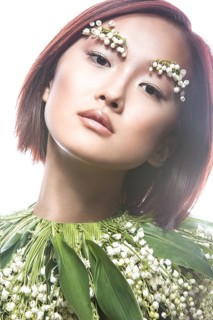 Fashion beautiful girl oriental type with delicate natural make-up and flowers. Beauty face. Picture taken in the studio on a white background