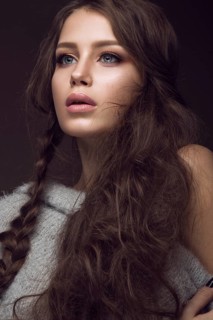Beautiful young girl with gentle make-up in warm sweater and long straight hair. Beauty face. Studio portrait