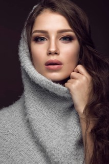 Beautiful young girl with gentle make-up in warm sweater and long straight hair. Beauty face. Studio portrait