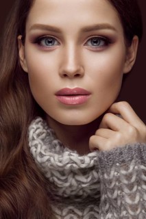 Beautiful young girl with gentle make-up in warm sweater and long straight hair. Beauty face. Studio portrait