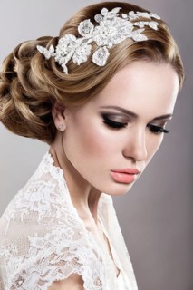 Portrait of a beautiful blonde woman in the image of the bride with flowers in her hair. Picture taken in the studio on a blue background