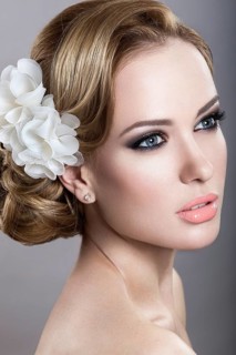 Portrait of a beautiful blonde woman in the image of the bride with flowers in her hair. Picture taken in the studio on a blue background
