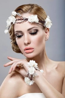 Portrait of a beautiful blonde woman in the image of the bride with flowers in her hair. Picture taken in the studio on a blue background