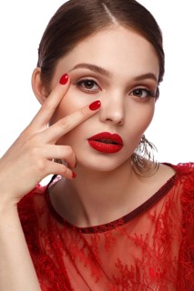 Beautiful girl in red dress with classic make-up and red manicure. Beauty face. Photo taken in the studio