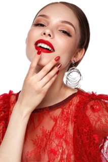 Beautiful girl in red dress with classic make-up and red manicure. Beauty face. Photo taken in the studio