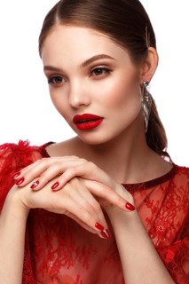 Beautiful girl in red dress with classic make-up and red manicure. Beauty face. Photo taken in the studio