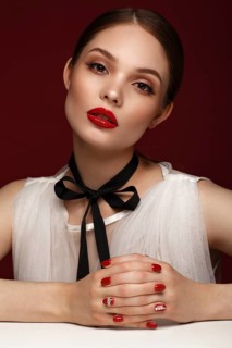 Beautiful girl in white dress with classic make-up and red manicure. Beauty face. Photo taken in the studio