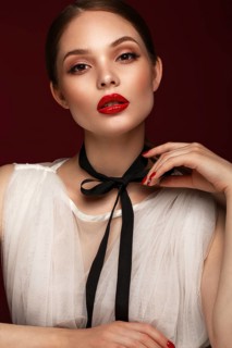 Beautiful girl in white dress with classic make-up and red manicure. Beauty face. Photo taken in the studio