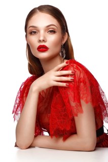Beautiful girl in red dress with classic make-up and red manicure. Beauty face. Photo taken in the studio