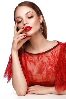 Beautiful girl in red dress with classic make-up and red manicure. Beauty face. Photo taken in the studio