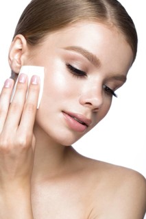 Beautiful young girl with wipes for removing makeup and French manicure. Beauty face. Picture taken in the studio on a white background