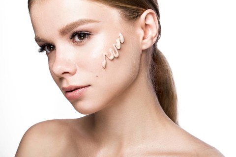 Beautiful young girl with tone cream on her skin. Beauty face. Picture taken in the studio on a white background