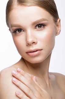Beautiful young girl with a light natural make-up and French manicure. Beauty face. Picture taken in the studio on a white background