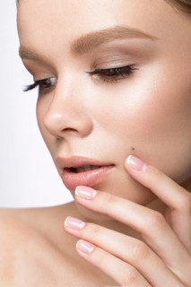 Beautiful young girl with a light natural make-up and French manicure. Beauty face. Picture taken in the studio on a white background