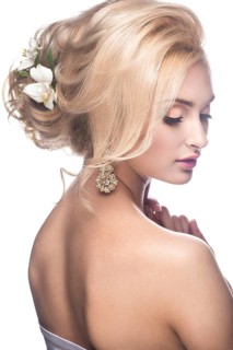 Beautiful blond girl in the image of a bride with flowers in her hair. Picture taken in the studio on a white background. Beauty face. Wedding image